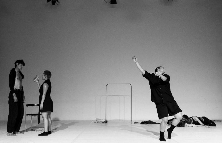 Dancer reaching upward on a white stage, black and white